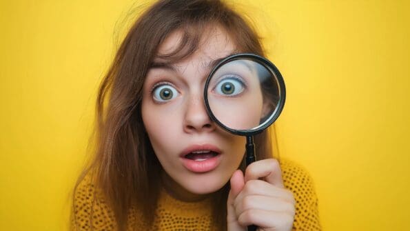 curious girl lookin through magnifying glass