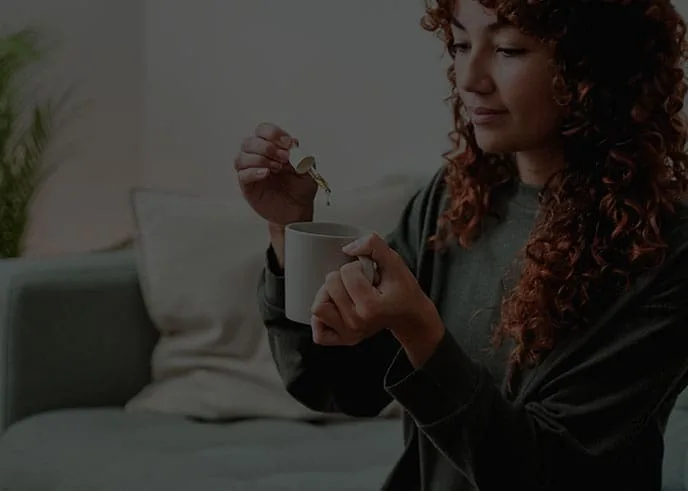woman putting cbd oil into her drink