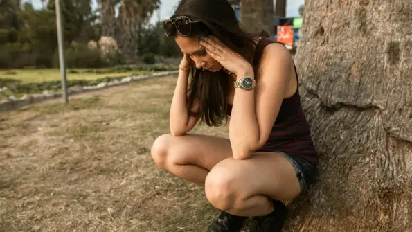 picture of a woman outdoors crouched having an anxiety attack